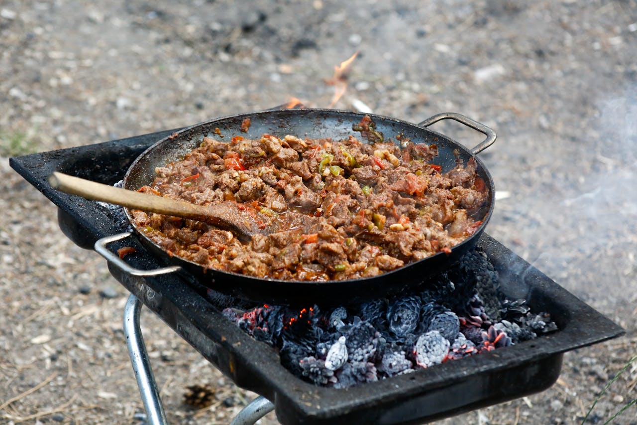 services-01 A savory meat stew cooking over an open fire, ideal for outdoor adventures and barbecue enthusiasts.