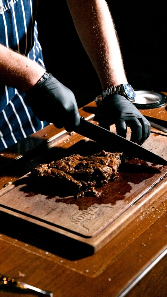 Chef slicing a juicy steak on a wooden board in a restaurant kitchen.