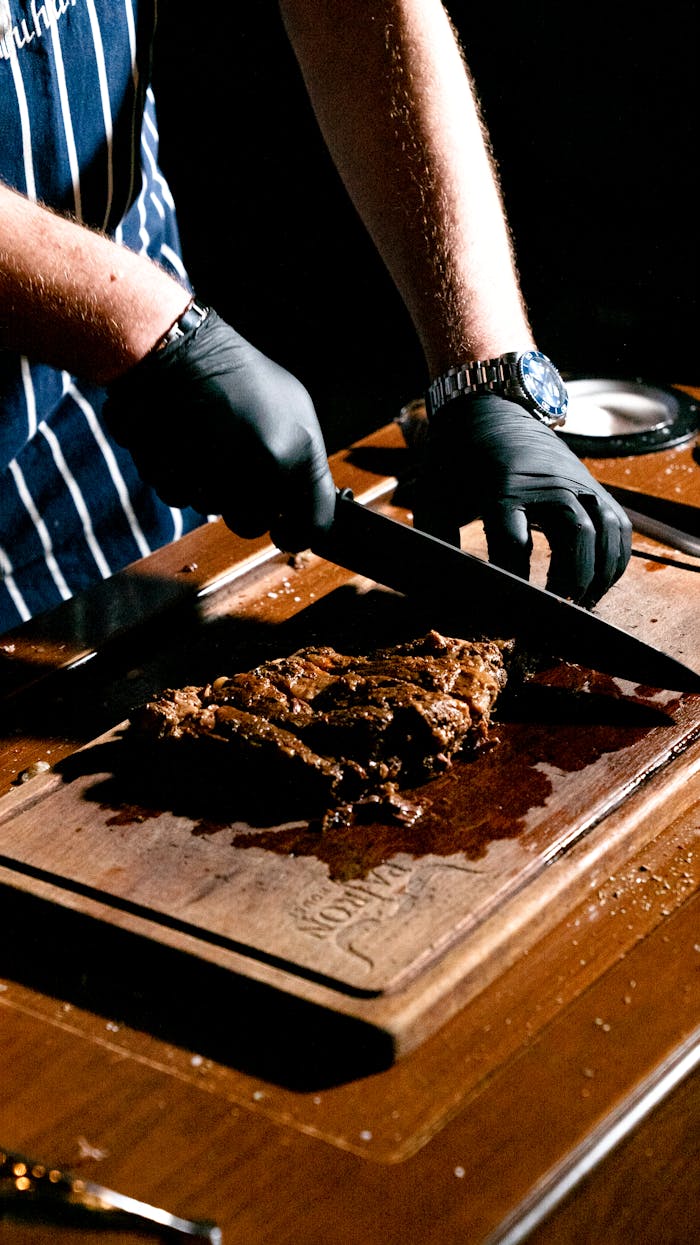 gallery-05 Chef slicing a juicy steak on a wooden board in a restaurant kitchen.